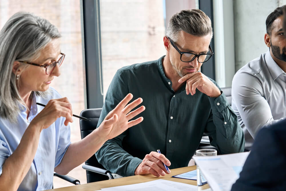 Three people sitting at a table working on a document.